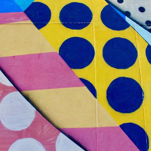 Vibrant geometric wall mural with bold colors and patterns featuring circles and stripes.